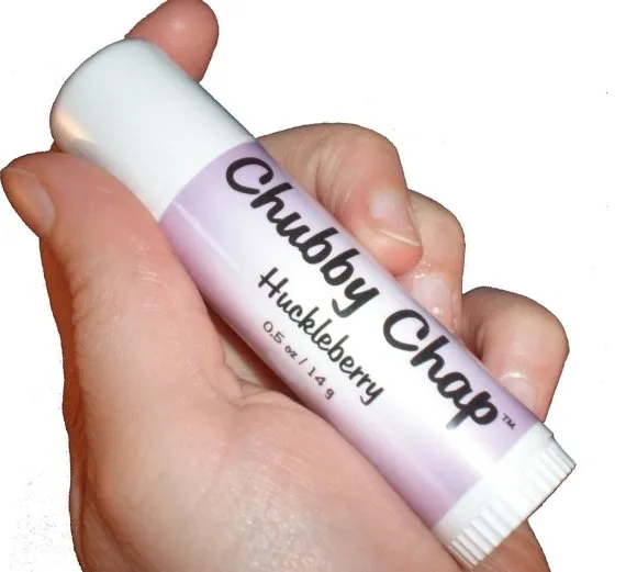 A person holding a tube of chubby chap huckleberry lip balm.